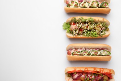 Photo of Delicious hot dogs with different toppings on white background, flat lay. Space for text