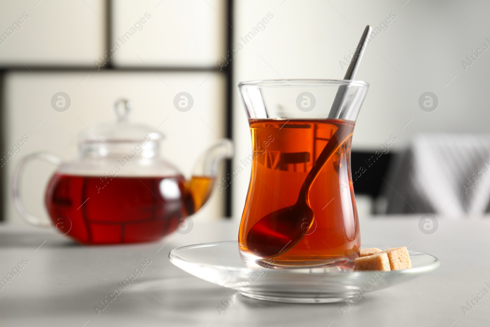 Photo of Traditional Turkish tea in glass and sugar cubes on white table, closeup. Space for text