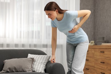 Photo of Woman having heart attack near sofa at home