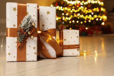 Photo of Beautiful gift boxes against fir tree with Christmas lights at home