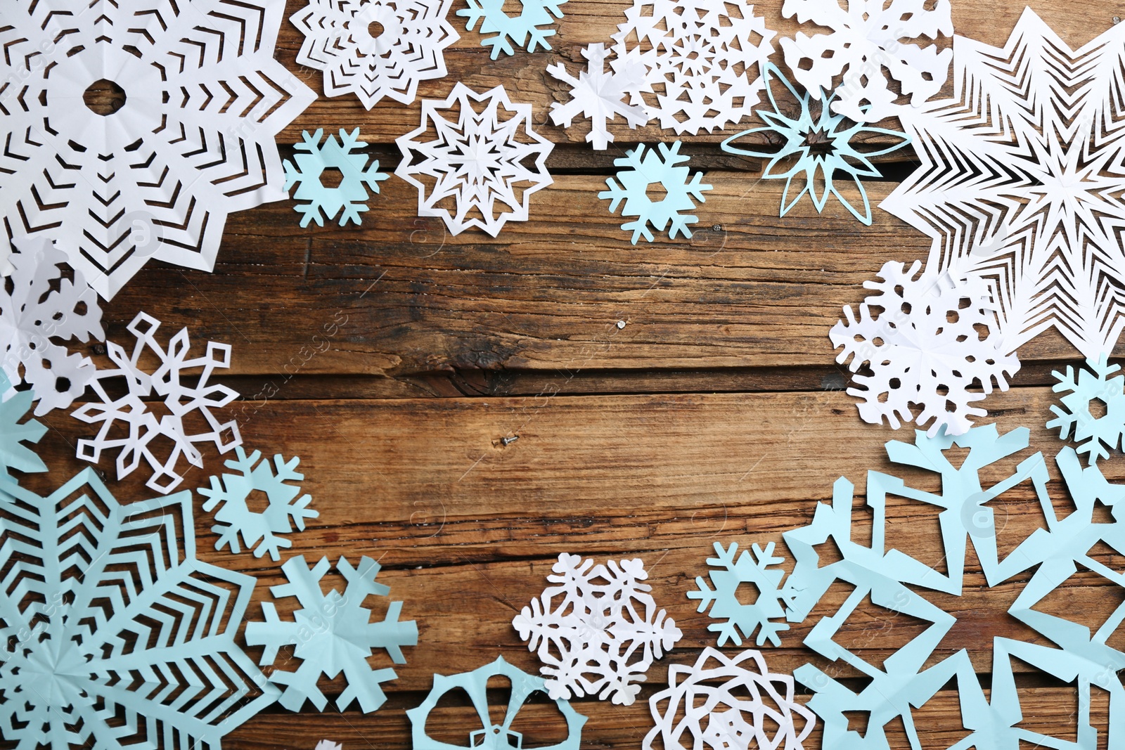 Photo of Many paper snowflakes on wooden background, flat lay. Space for text