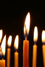 Many burning church candles on dark background, closeup