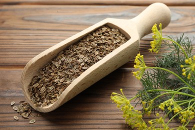 Photo of Scoop of dry seeds and fresh dill on wooden table, closeup