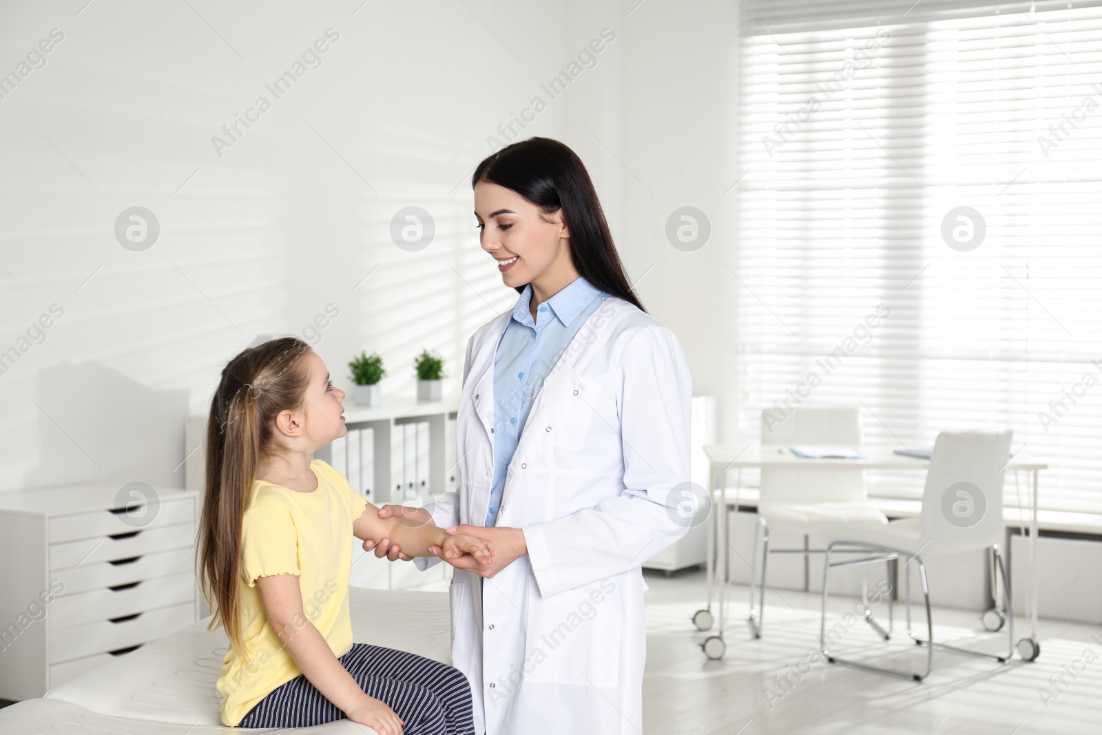 Photo of Professional orthopedist examining little patient's arm in clinic