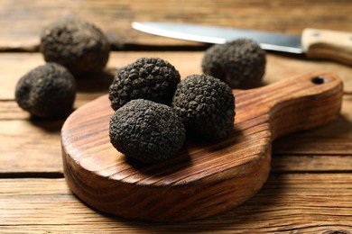 Photo of Black truffles with board on wooden table
