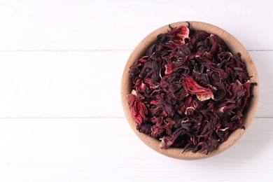 Photo of Dry hibiscus tea in bowl on white wooden table, top view. Space for text