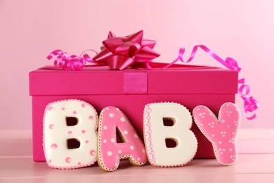 Word BABY made of tasty cookies and gift box on pink wooden table