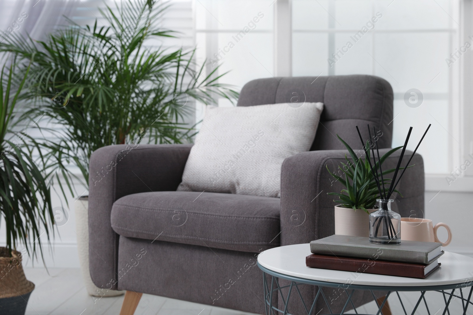 Photo of Comfortable place for rest with grey armchair near window indoors