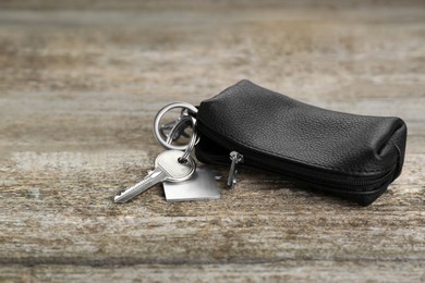 Photo of Leather case with key on old wooden table, closeup. Space for text