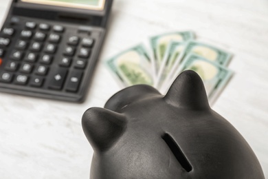 Photo of Black piggy bank near money and calculator on table