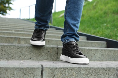 Photo of Man in stylish black sneakers walking down stairs, closeup