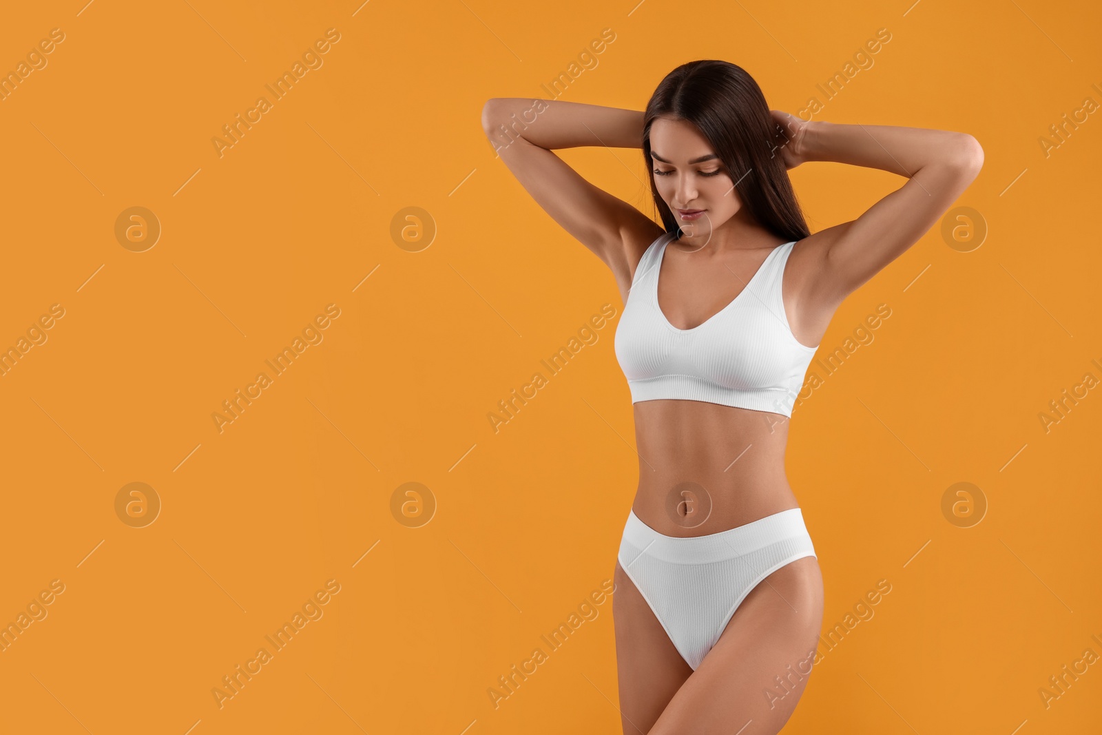 Photo of Young woman in stylish white bikini on orange background. Space for text