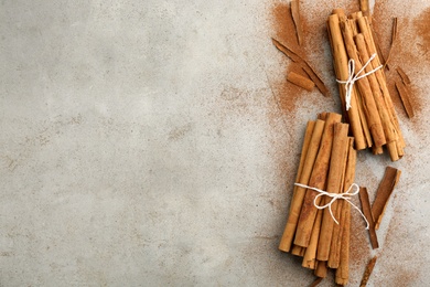 Aromatic cinnamon sticks and powder on grey table, flat lay. Space for text