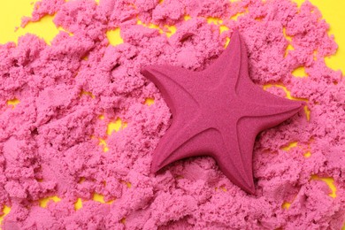 Star made of kinetic sand on yellow background, flat lay