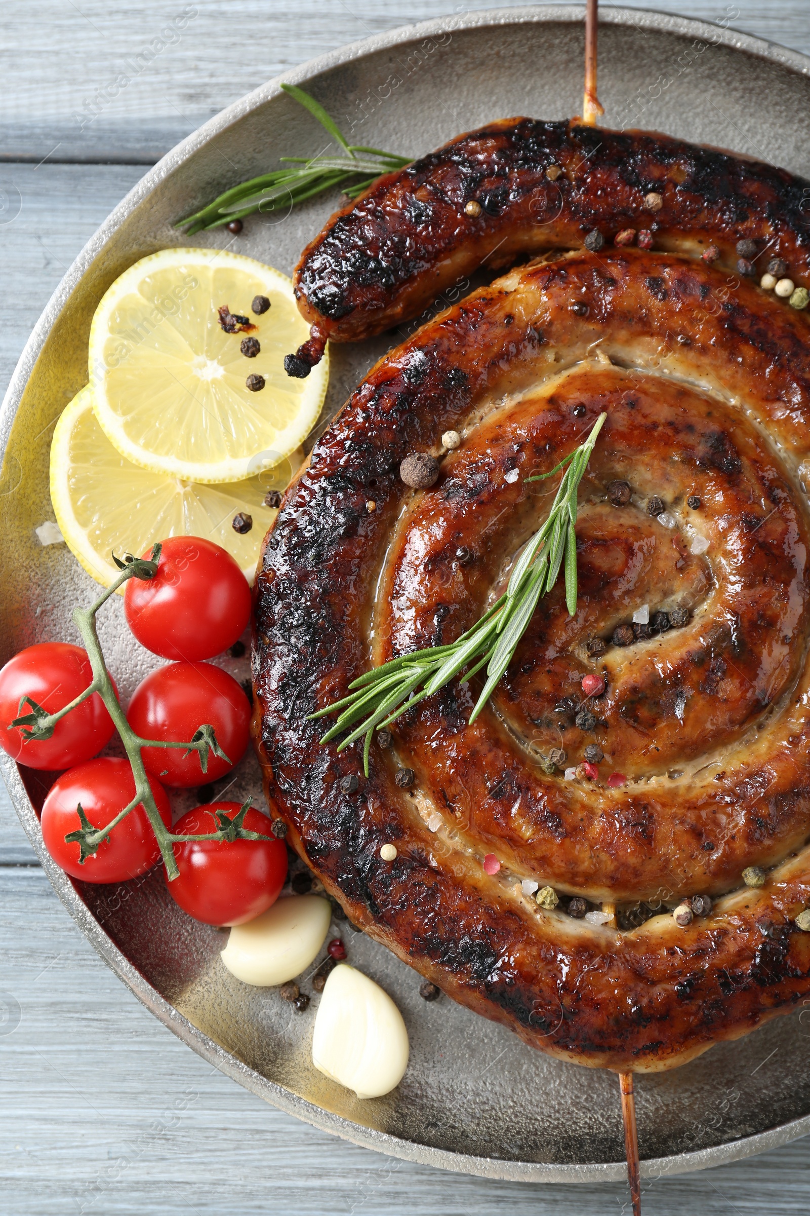 Photo of Delicious homemade sausage with spices, tomatoes and lemon on light grey wooden table, top view