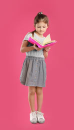 Little girl with book on pink background