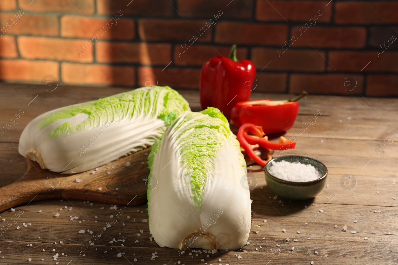 Photo of Fresh Chinese cabbages, bell peppers and salt on wooden table