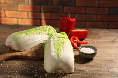 Fresh Chinese cabbages, bell peppers and salt on wooden table