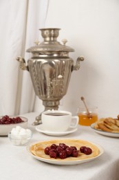 Vintage samovar, cup of hot drink and snacks served on table. Traditional Russian tea ceremony