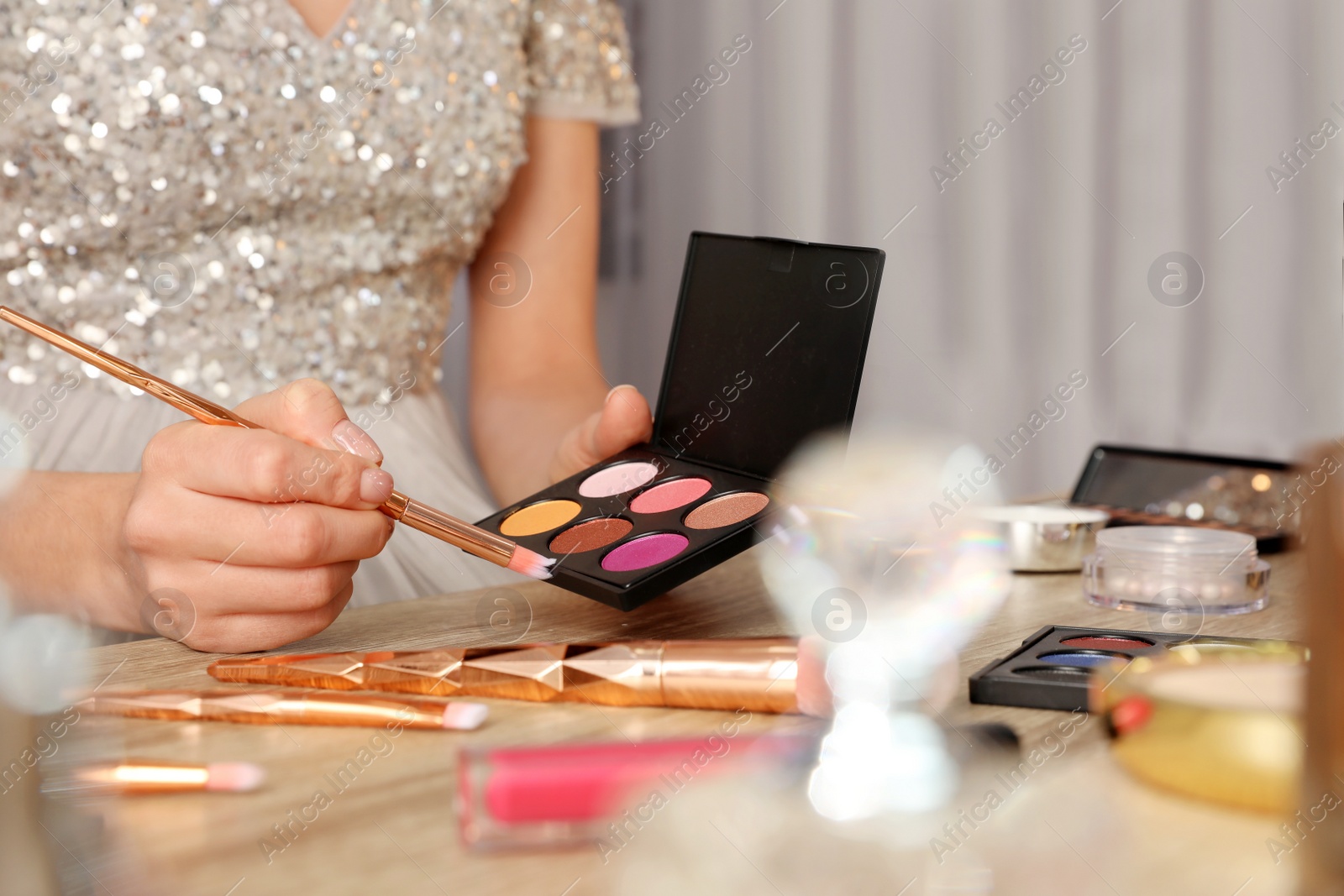 Photo of Woman applying makeup at dressing table, closeup