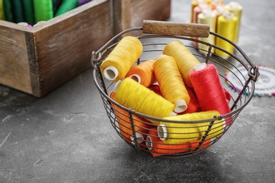 Photo of Metal basket with color sewing threads on grey background