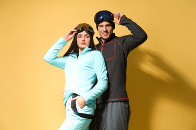 Couple wearing stylish winter sport clothes on yellow background