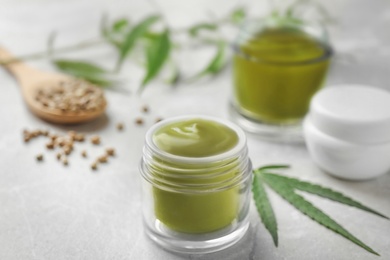 Photo of Jars of hemp cream and seeds on grey table. Organic cosmetics