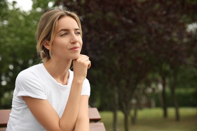 Photo of Beautiful young woman sitting on bench in park