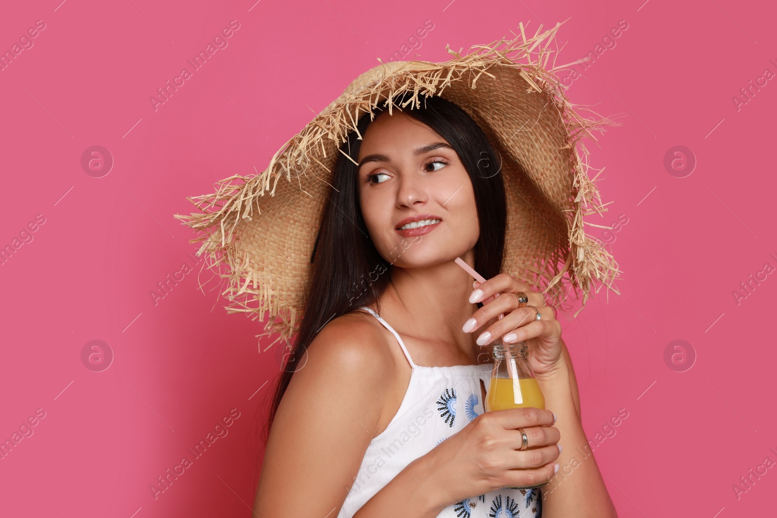 Photo of Beautiful young woman with straw hat and bottle of refreshing drink on pink background