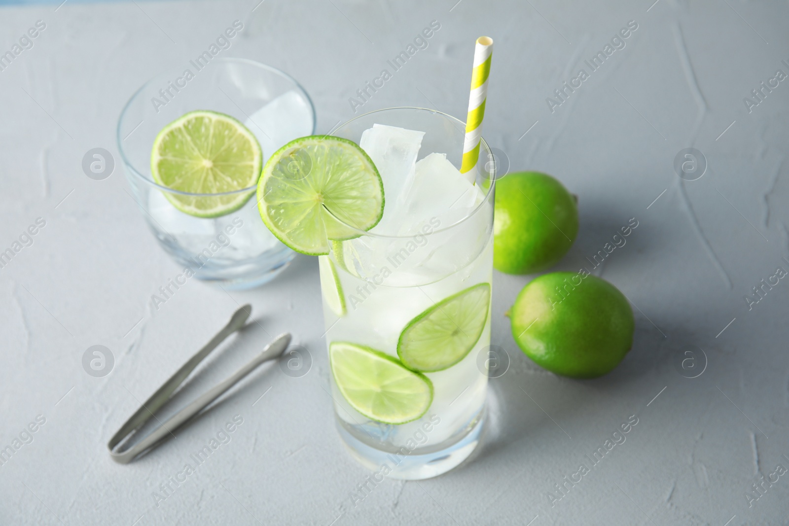 Photo of Glass of drink with lime and ice cubes on table
