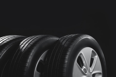 Photo of New car tires with rims on black background, closeup