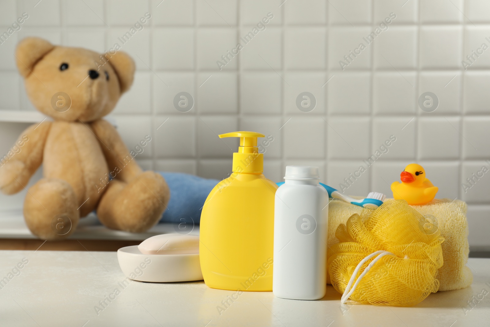 Photo of Baby cosmetic products, bath duck, sponge and towel on white table indoors