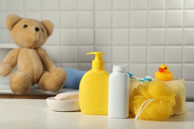 Photo of Baby cosmetic products, bath duck, sponge and towel on white table indoors