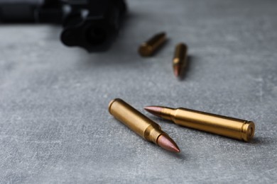 Photo of Bullets and handgun on light grey table, closeup. Space for text