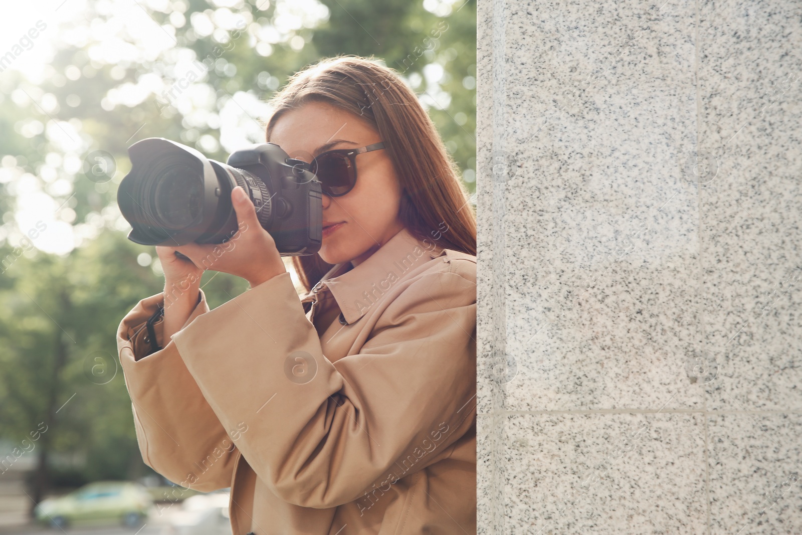 Photo of Private detective with camera spying near building on city street