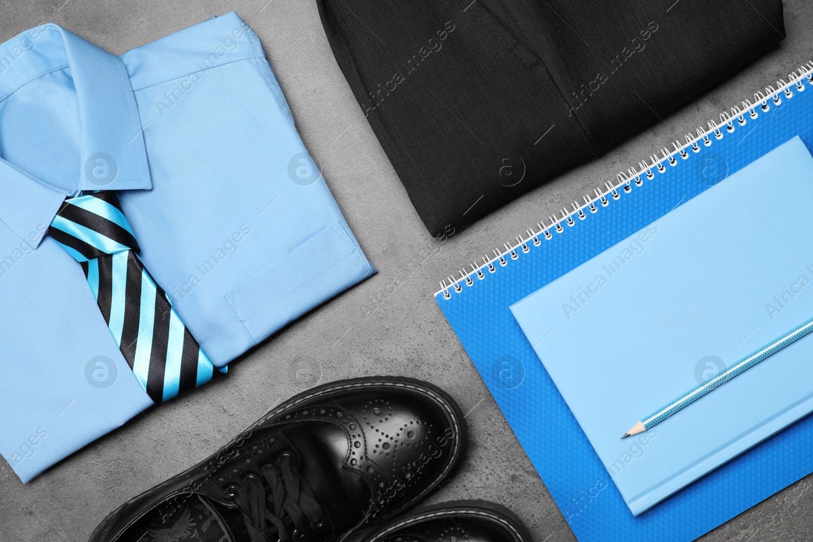 Photo of Stylish school uniform for boy and stationery on grey background, flat lay