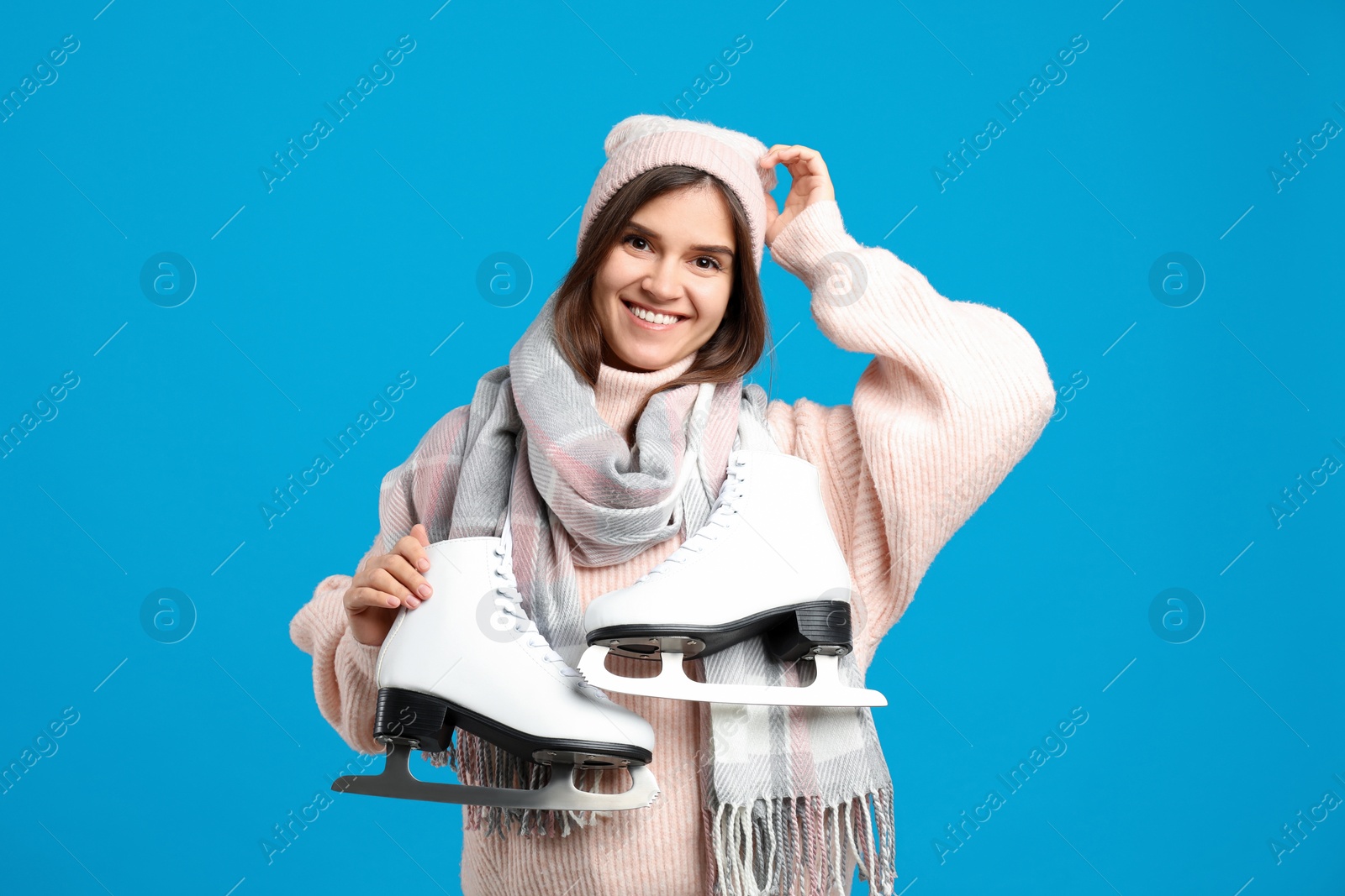 Photo of Happy woman with ice skates on light blue background