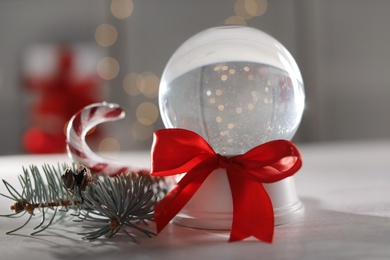 Christmas snow globe with red bow on table