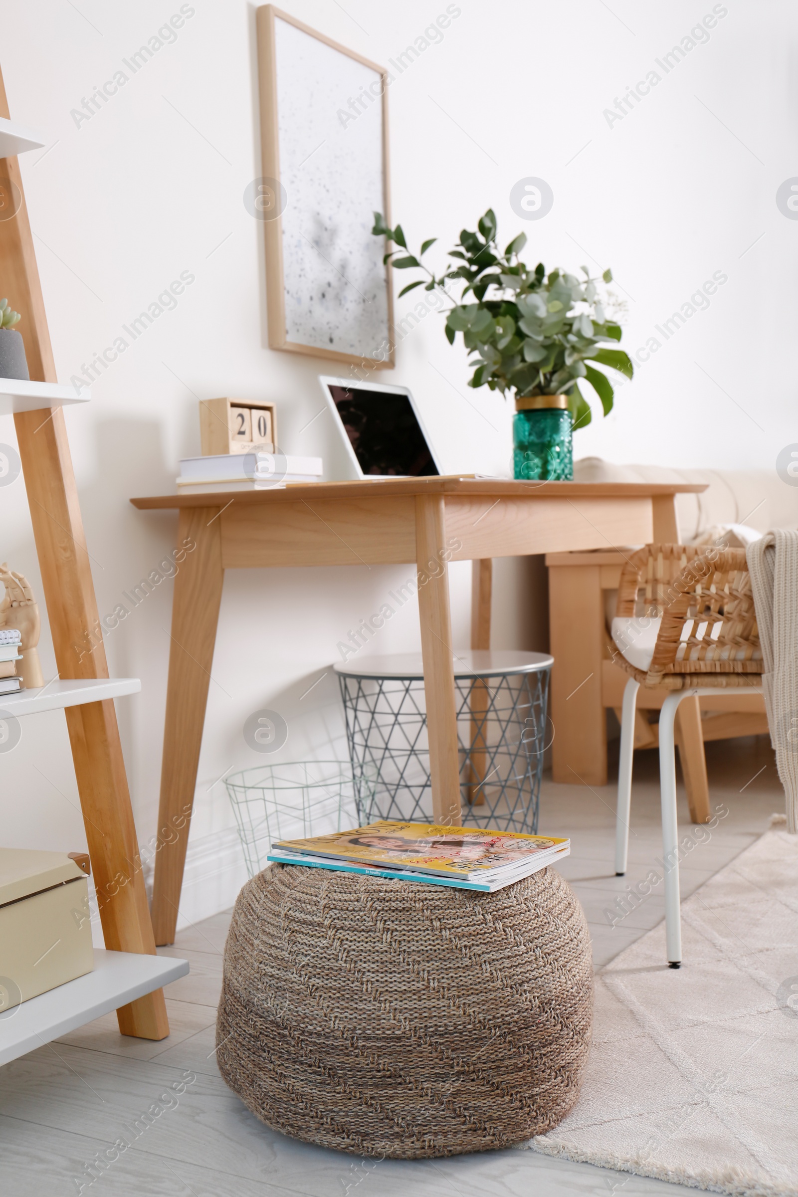 Photo of Stylish knitted pouf with magazines on floor in modern home office. Interior design