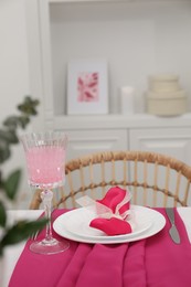 Table setting. Glass of tasty beverage, plates with pink napkin and cutlery in dining room