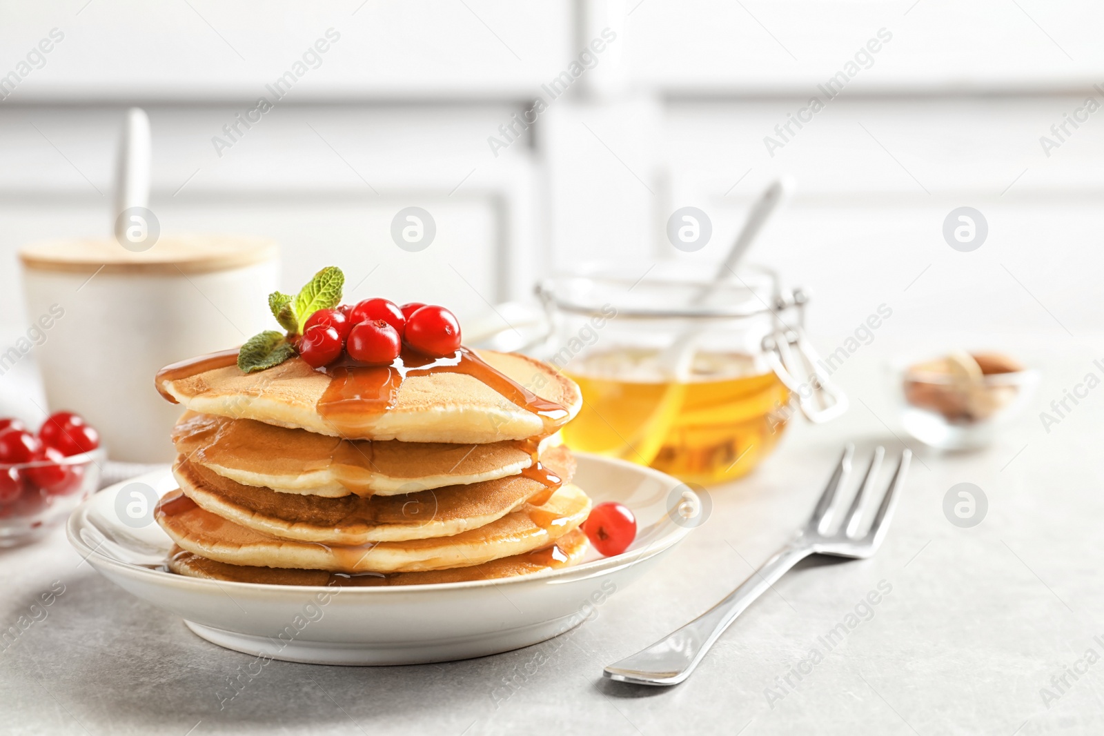 Photo of Stack of tasty pancakes with berries and syrup on table