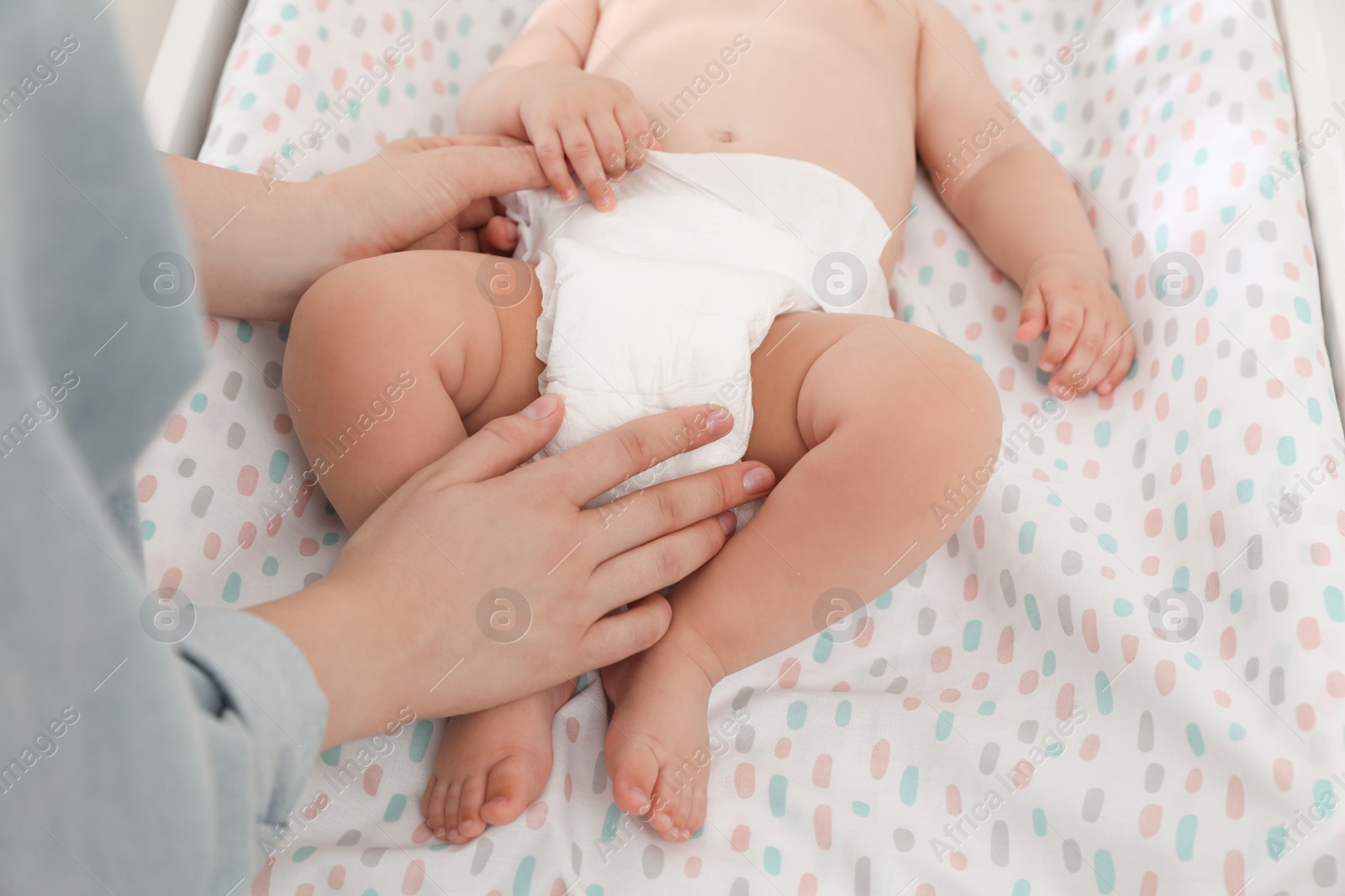 Photo of Mother changing baby's diaper on table, closeup