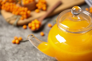 Photo of Delicious sea buckthorn tea in teapot, closeup