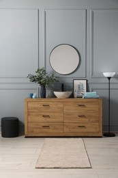 Modern bathroom interior with stylish mirror, eucalyptus branches, vessel sink and wooden vanity