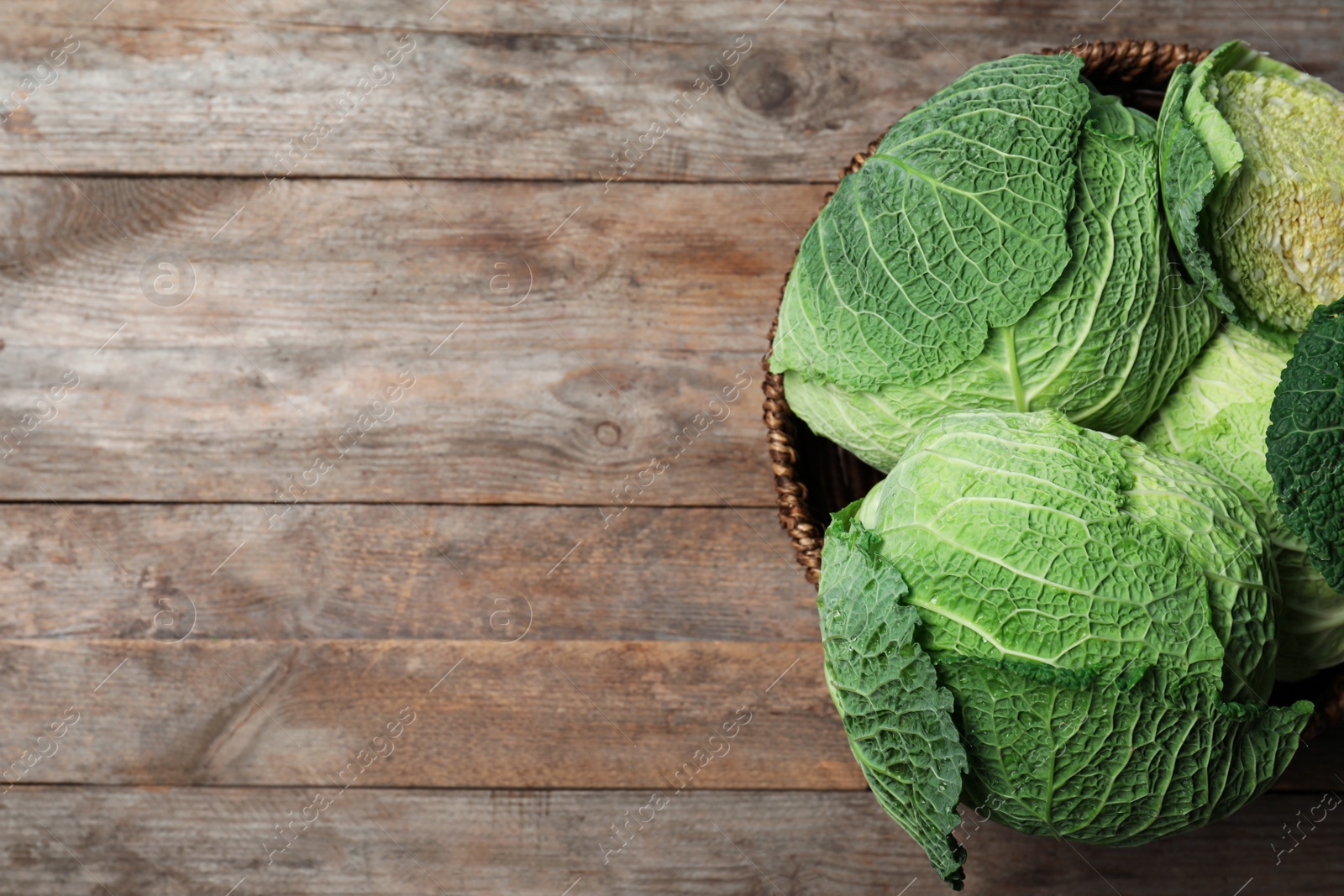 Photo of Bowl with savoy cabbage and space for text on wooden background, top view