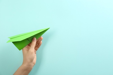 Photo of Woman holding paper plane on light blue background, closeup. Space for text