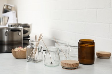 Photo of Glass jars with wicks and dry flowers near homemade candles on kitchen counter