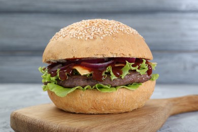 Photo of Delicious cheeseburger with lettuce, onion, ketchup and patty on table, closeup