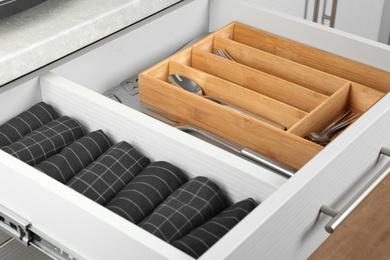 Photo of Open drawer with different utensils and folded towels. Order in kitchen