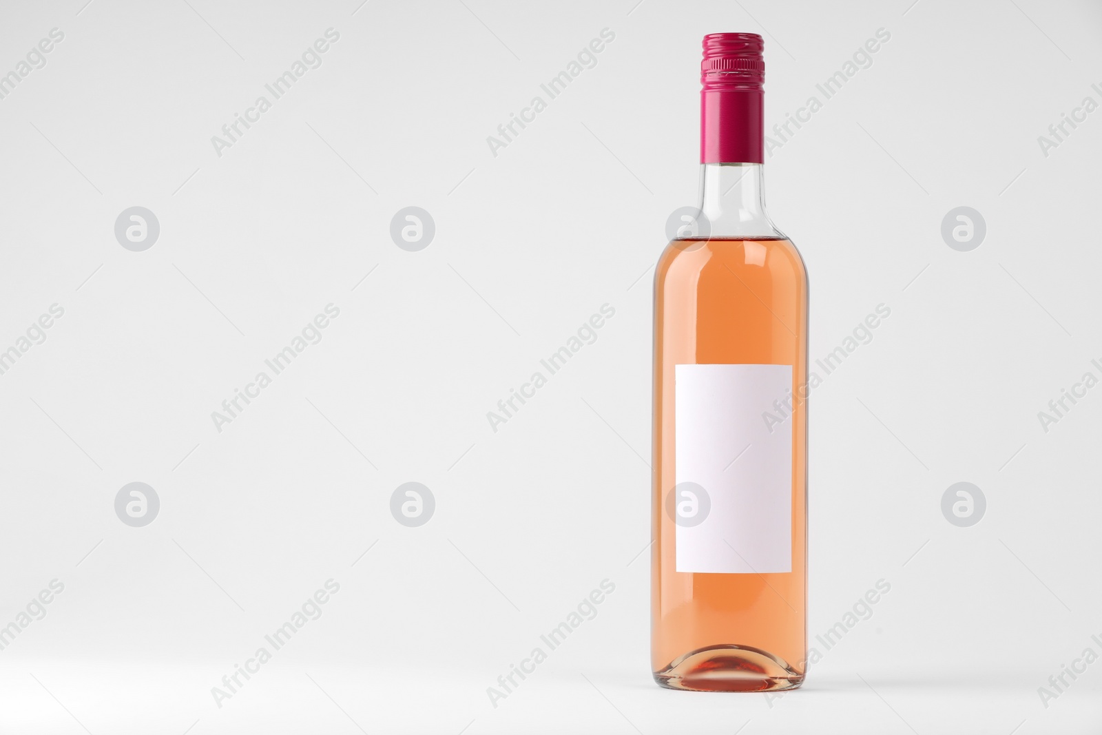 Photo of Bottle of tasty rose wine on white background, space for text